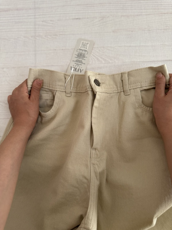 نمای جلوی شلوار کتان بگ سنگشور شیری، با دکمه و زیپ فلزی، جیبهای جادار و کمربند محکم