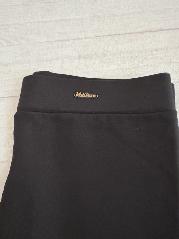 لگ نخی زنانه مشکی با کمر کشی و طرح حروف انگلیسی هک شده، نمای جلو روی زمین