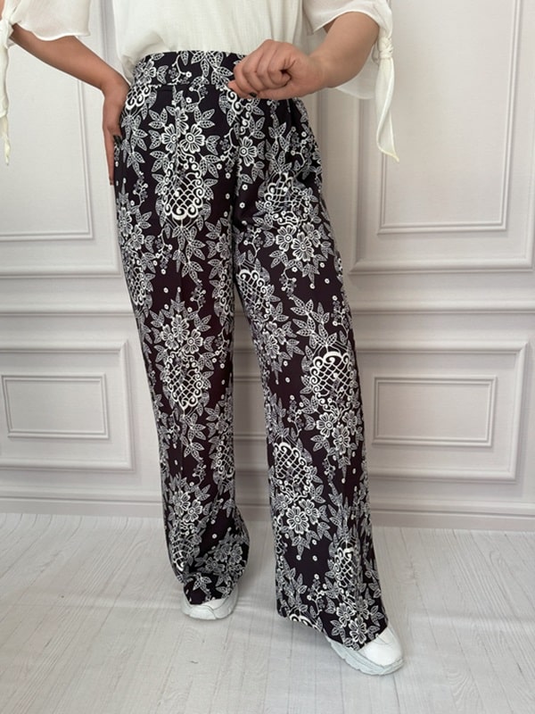 شلوار پارچهای بگ زنانه با طرح گل و برگ سفید روی زمینه مشکی، نمای بغل در تن مانکن