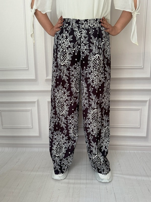 شلوار پارچهای بگ زنانه با طرح گل و برگ سفید روی زمینه مشکی، نمای جلو در تن مانکن