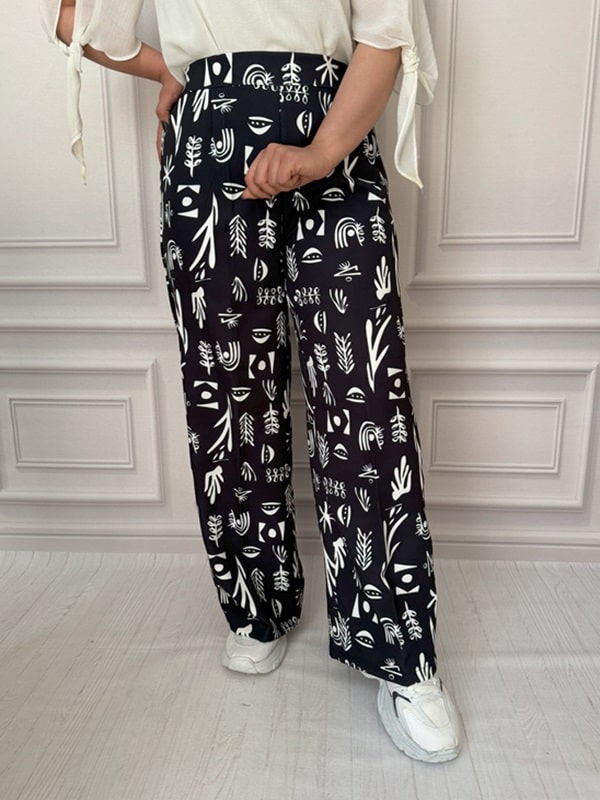 شلوار پارچهای بگ زنانه با طرح انتزاعی سفید روی زمینه مشکی، نمای جلو در تن مانکن