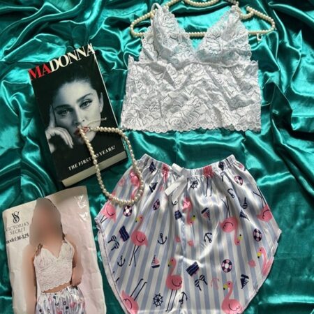 نمای کامل ست لباس خواب فانتزی شامل نیم‌تنه گیپوری سفید و شورتک ساتن براق طرحدار با طرح فلامینگو و دریایی، چیدمان شده روی زمینه ساتن سبز با بسته‌بندی و دکور مجله