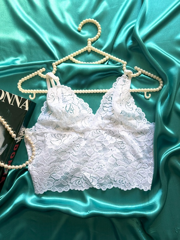 نمای نیم‌تنه گیپوری سفید از ست لباس خواب فانتزی زنانه، آویزان روی چوب‌لباسی مرواریدی با زمینه ساتن سبز و چیدمان دکوری