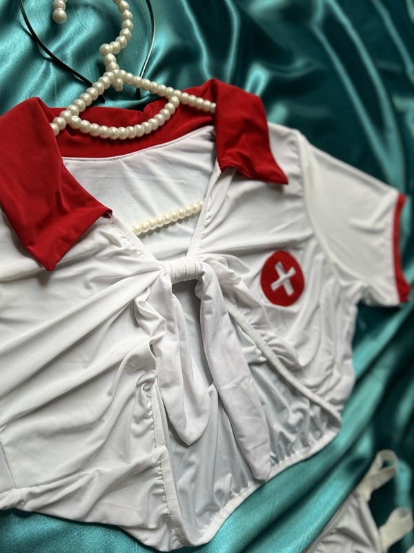 نمای نزدیک نیم تنه تیشرتی گره‌دار کاستوم پرستاری ۴ تکه، یقه برگردان قرمز، آرم صلیب و جنس ریون کشی لطیف